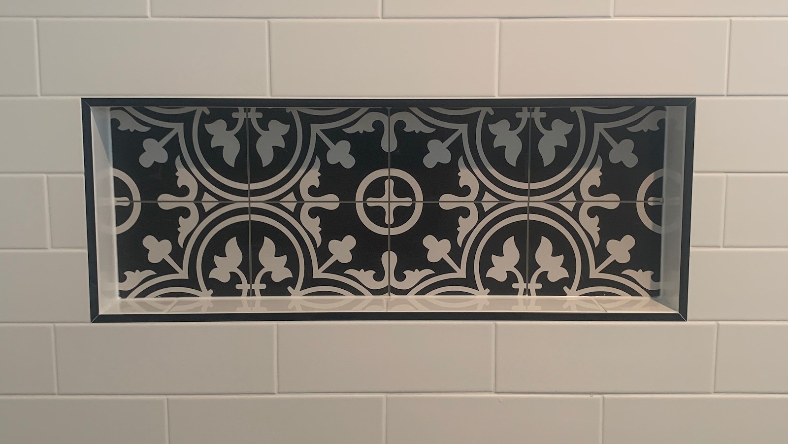A patterned feature tile panel set into a white brick wall