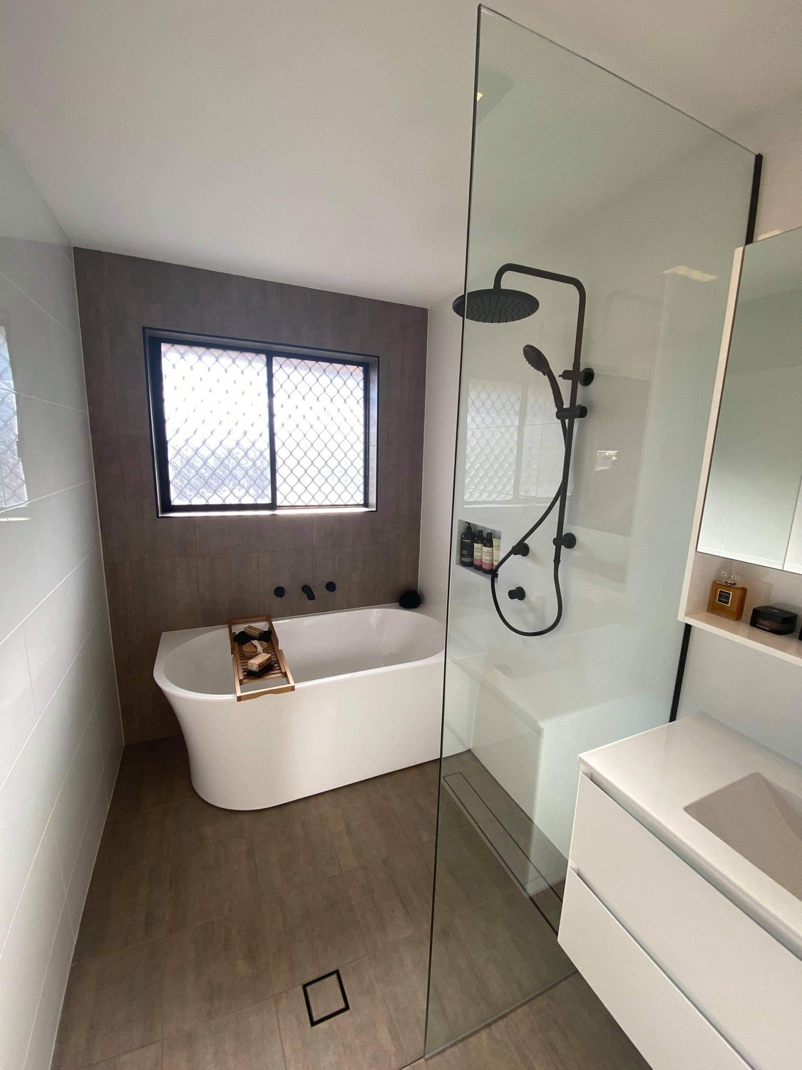 A renovated bathroom with a freestanding bath and full-height wall tiling
