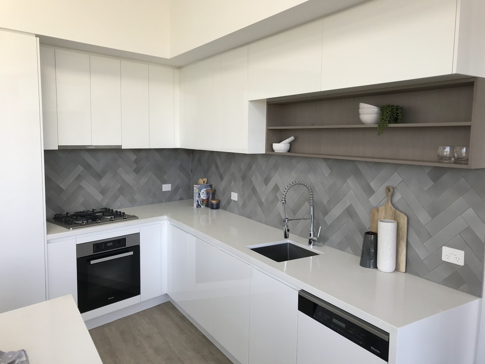 A finished kitchen with a grey herringbone splashback tiled by Clear Cut Tiling in the Shoalhaven