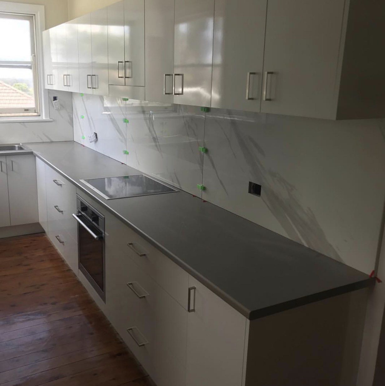 Kitchen wall tiling in progress with a marble-look splashback