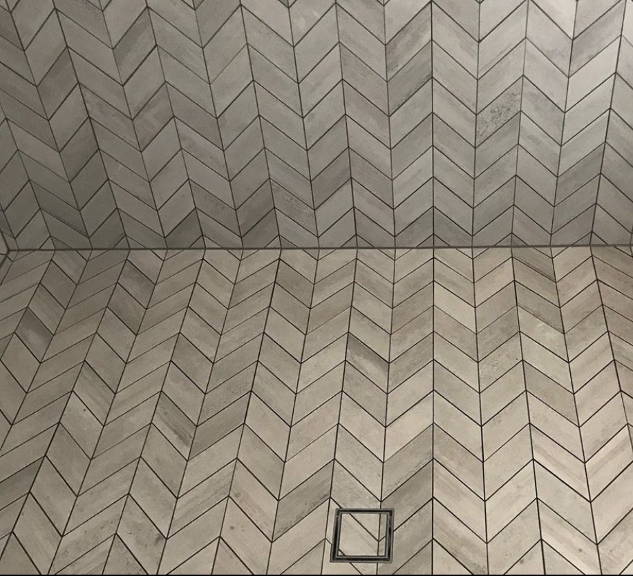 A chevron mosaic tiled floor with a recessed drain