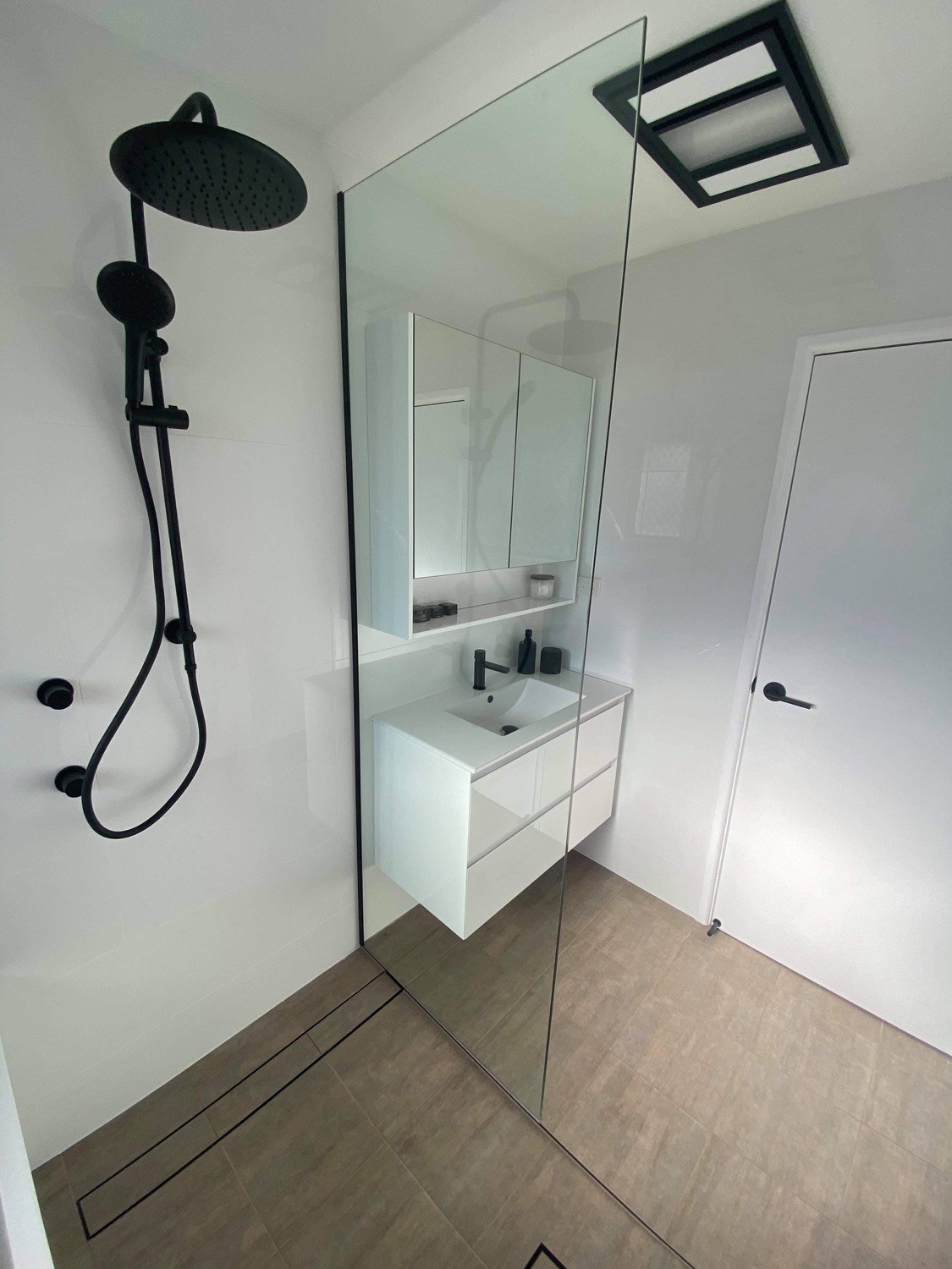A finished bathroom with matte black shower fittings and floor-to-ceiling tiles