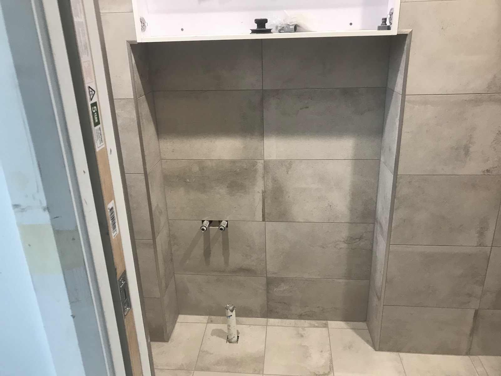 A shower recess with large-format grey wall tiles and a built-in niche