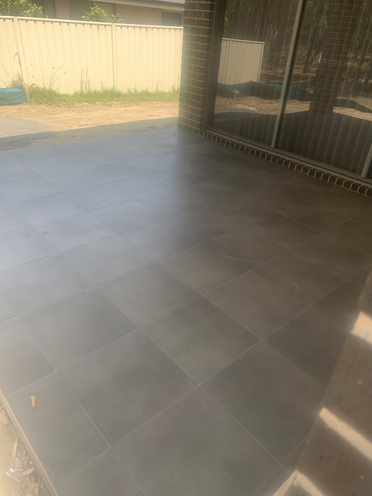Large-format floor tiles laid through a living area to glass sliding doors