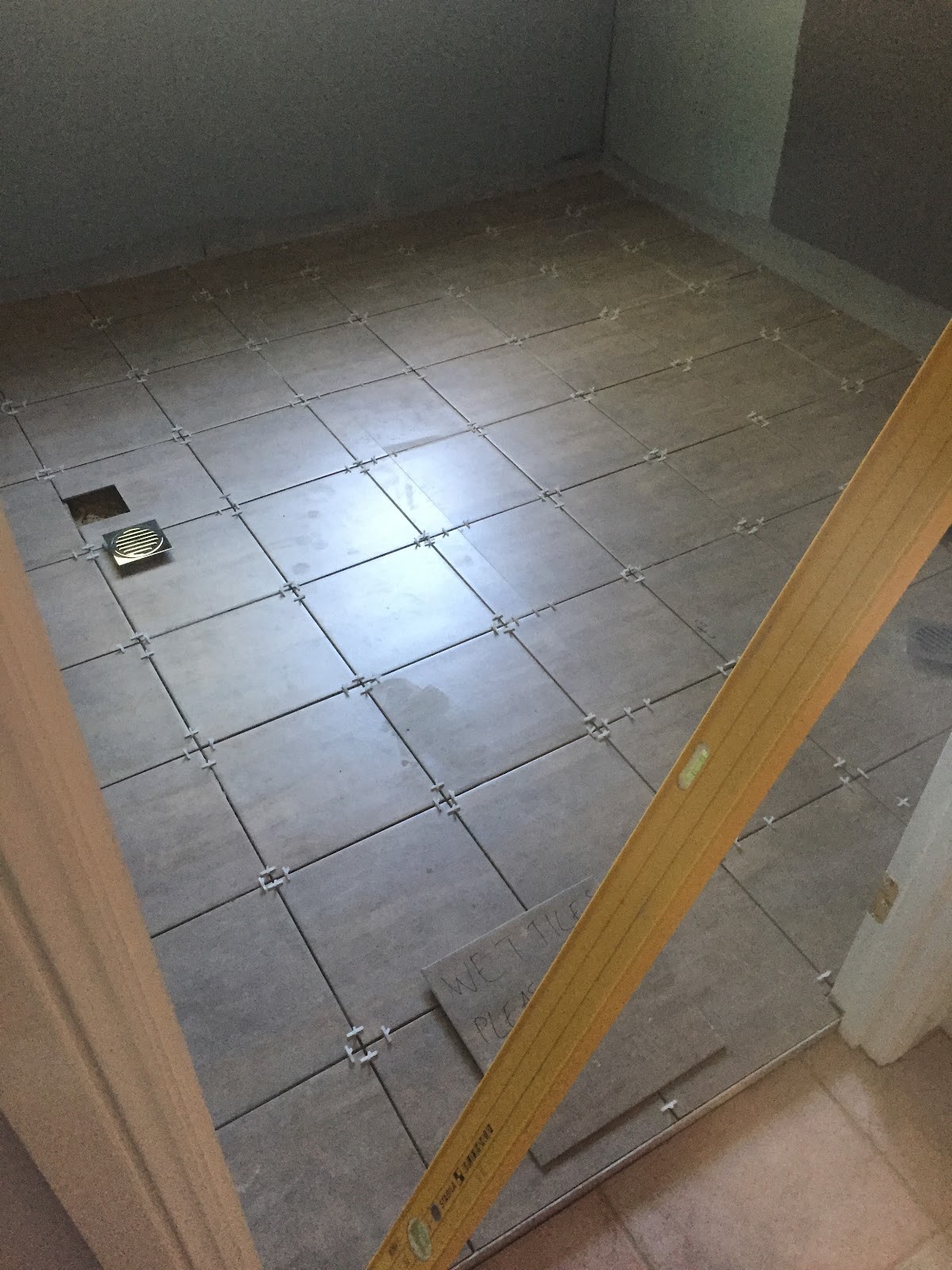 Floor tiles mid-lay with levelling spacers in place