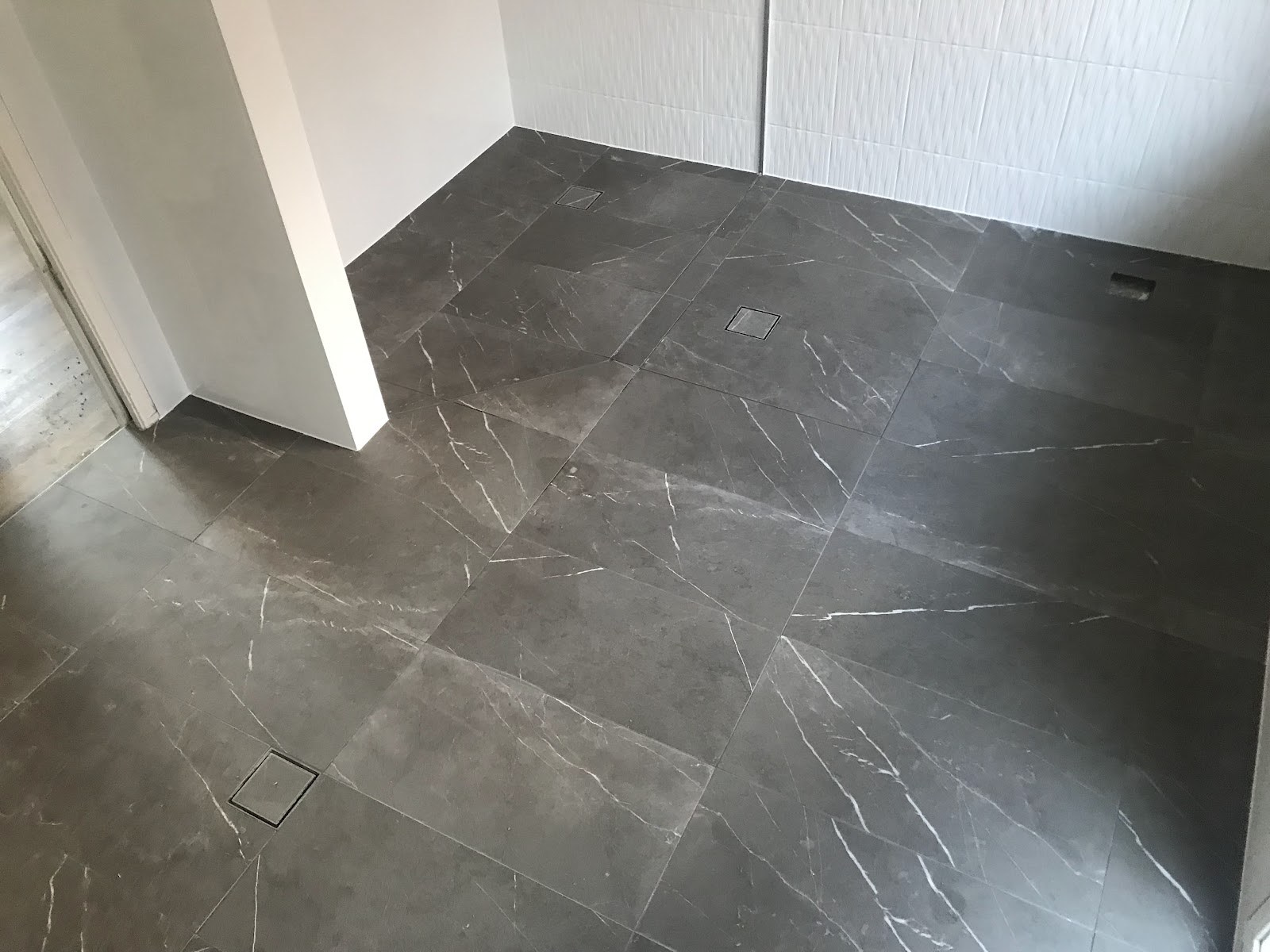 A dark marble-look tiled floor laid by Clear Cut Tiling