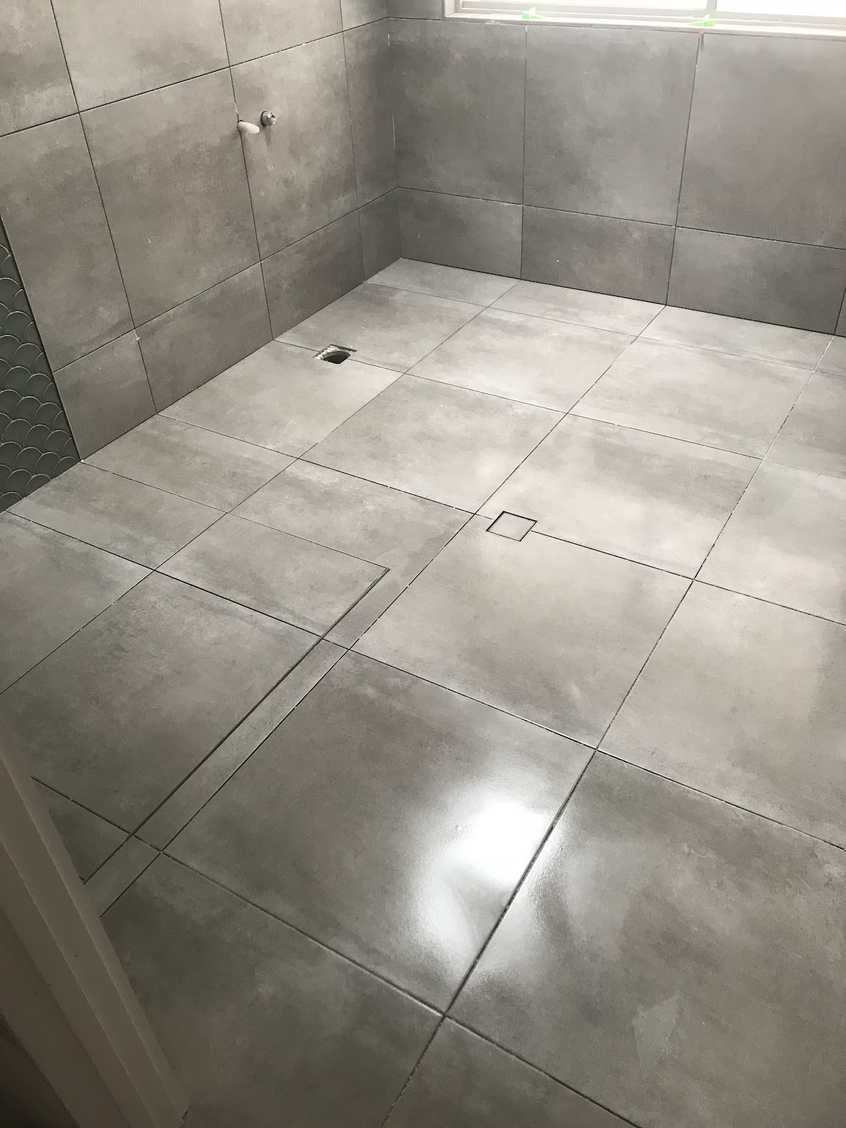 Grey floor tiles being laid with levelling clips